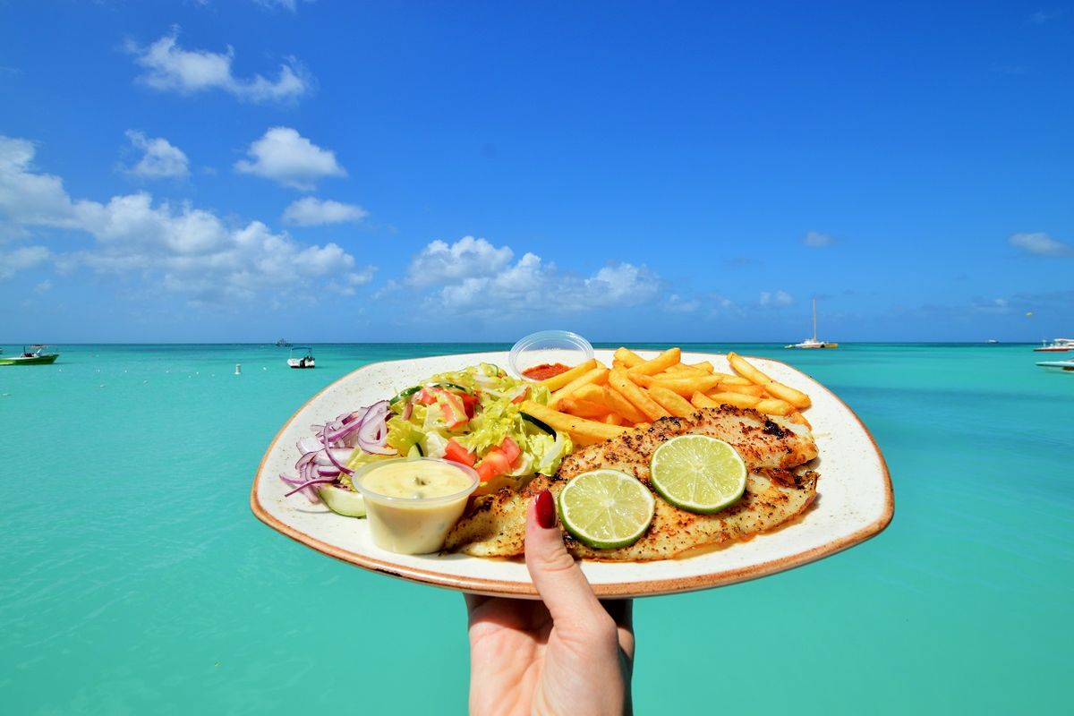 Lunch plate held up in front of the turquoise sea at Palm Beach
